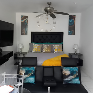 Modern bedroom with queen bed, bold yellow accents, ceiling fan, and wall art at Serenity Zen