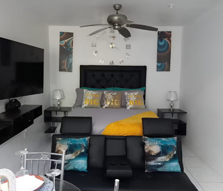 Modern bedroom with queen bed, bold yellow accents, ceiling fan, and wall art at Serenity Zen