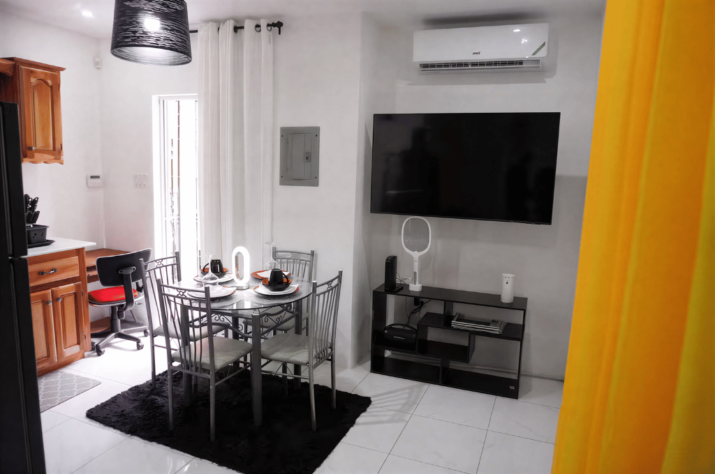 Modern living and dining area with TV and dining table at Mountain Echo Suites Montego Bay