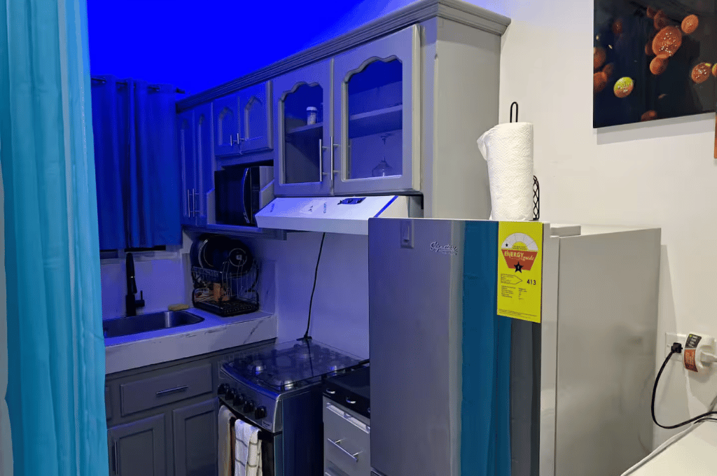 Fully equipped Serenity Vibes kitchen with cabinets, stovetop, microwave, fridge, and blue ambient lighting