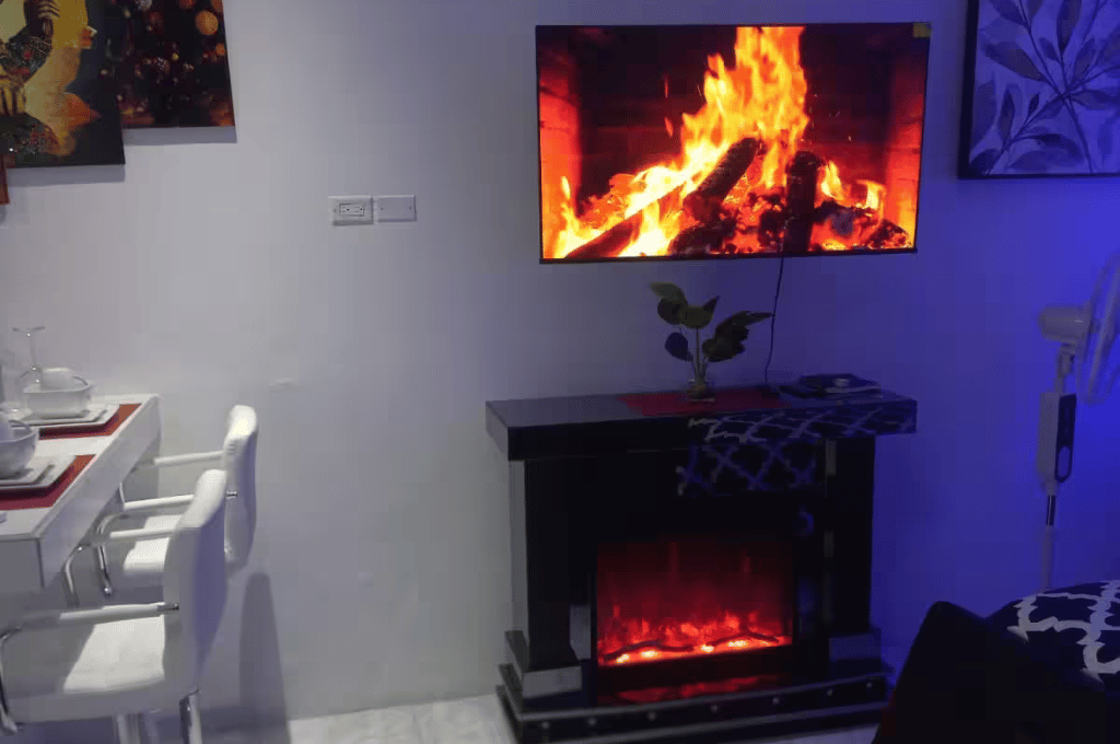 Electric fireplace in Serenity Vibes apartment living space with mounted TV and ambient lighting
