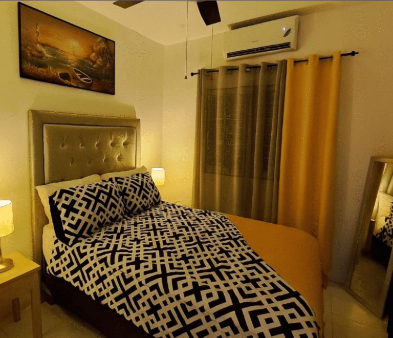Bedroom at Serenity Dream featuring gold curtains, geometric-patterned bedding, wall art, and air conditioning