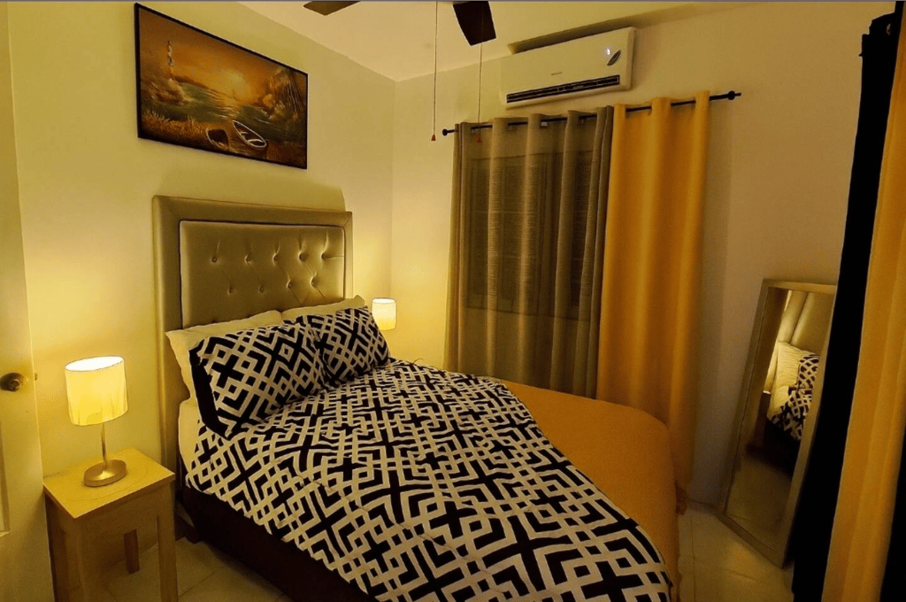 Bedroom at Serenity Dream featuring gold curtains, geometric-patterned bedding, wall art, and air conditioning